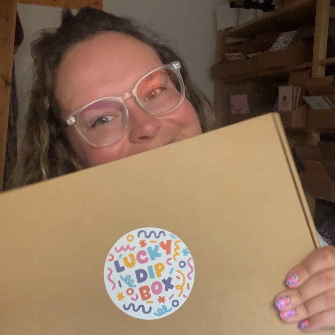 Person holding a cardboard box with a 'Lucky Dip Box' sticker in an indoor setting.